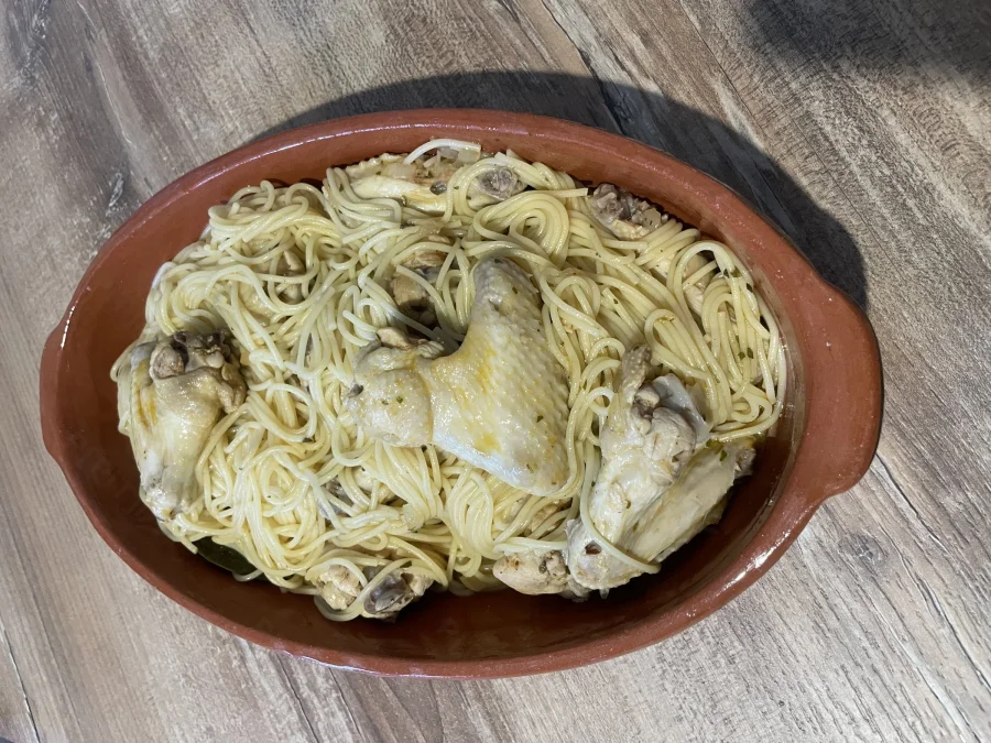 Ailes de poulet aux spaghettis servies dans un plat en terre cuite