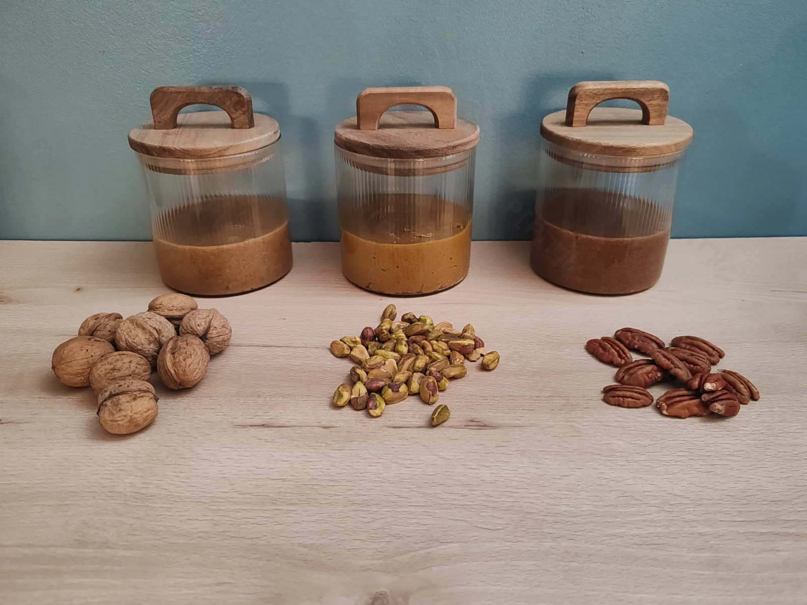 Trois pots de praliné maison : noix, pistache, et noix de pécan.